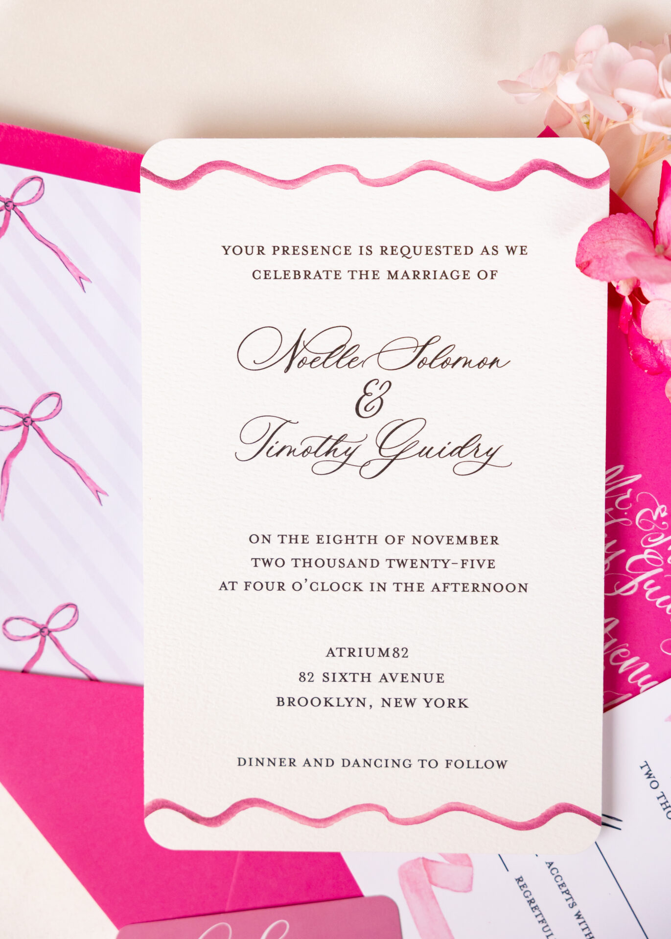 Pink watercolor wedding invitation with rounded corners and a hand-painted wave border on a fuchsia envelope
